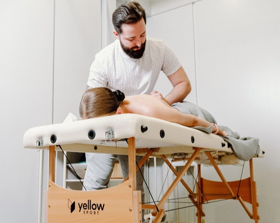Regeneracja masazysta pracuje na stole do masażu yellowSPORT